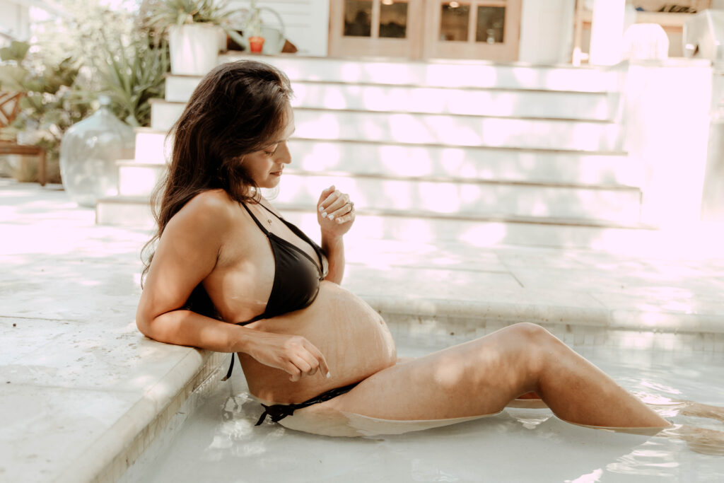 A pregnant woman posing for a photoshoot in a pool in an Asbury Park New Jersey home. 