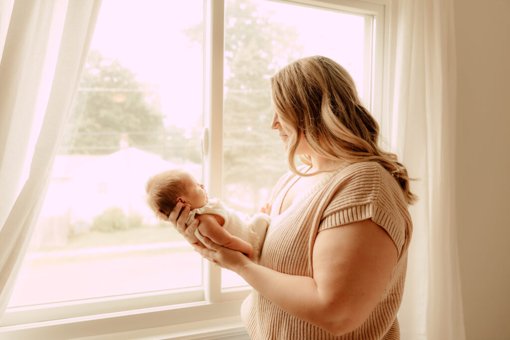 A mom holding a newborn baby during an-in home newborn session in New Jersey.